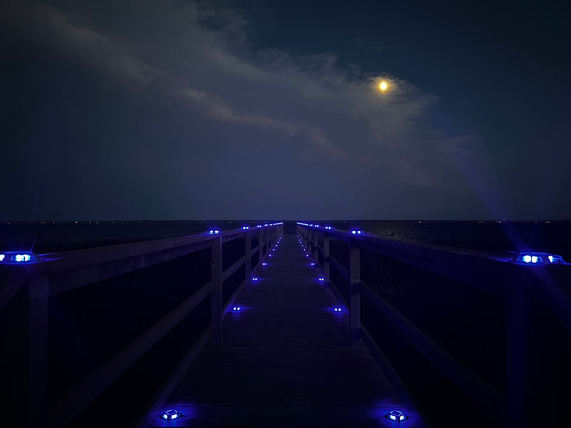 Straight view down the illuminated boardwalk toward the bay
