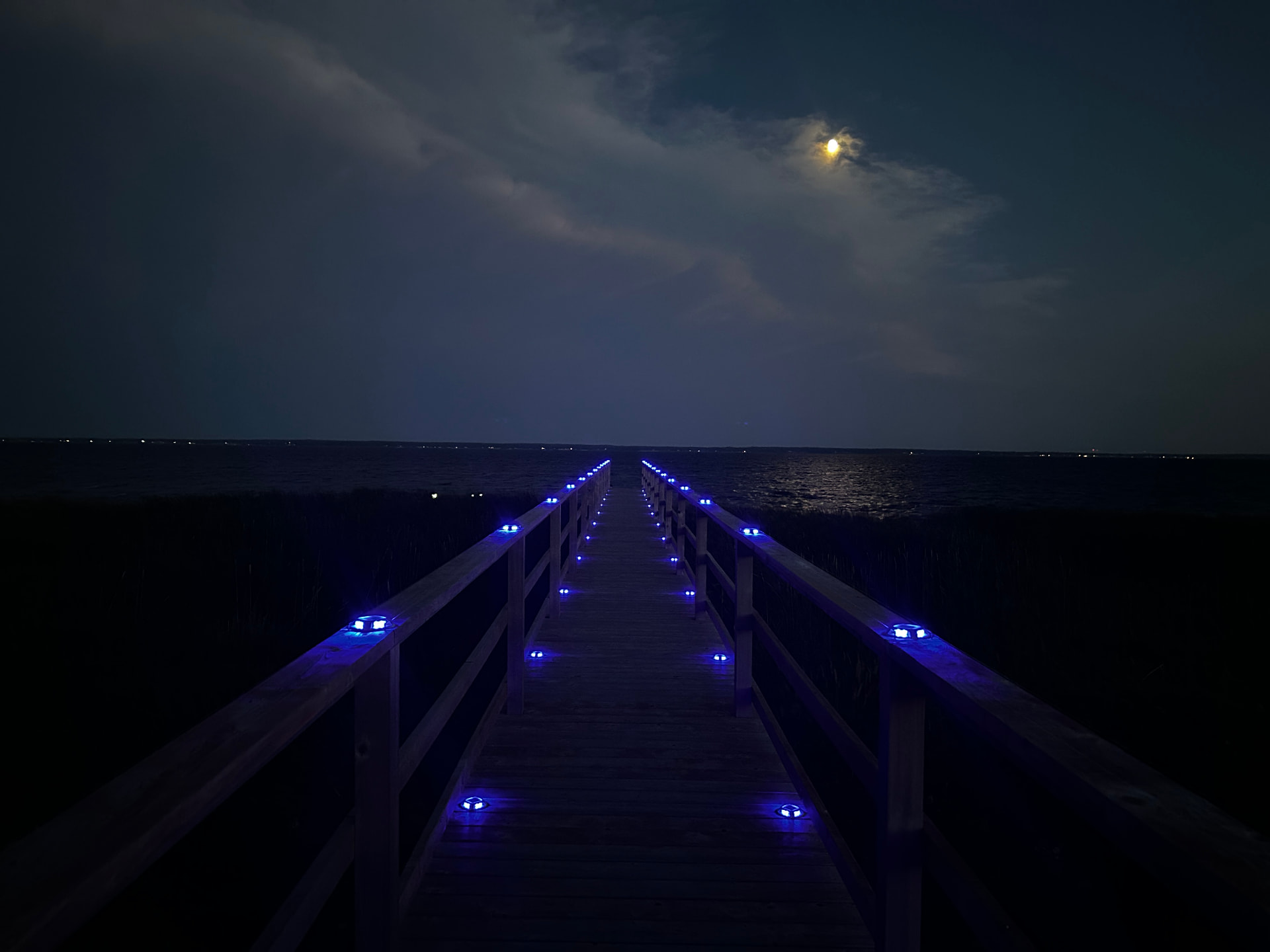 Glowing boardwalk leading over the dunes at night