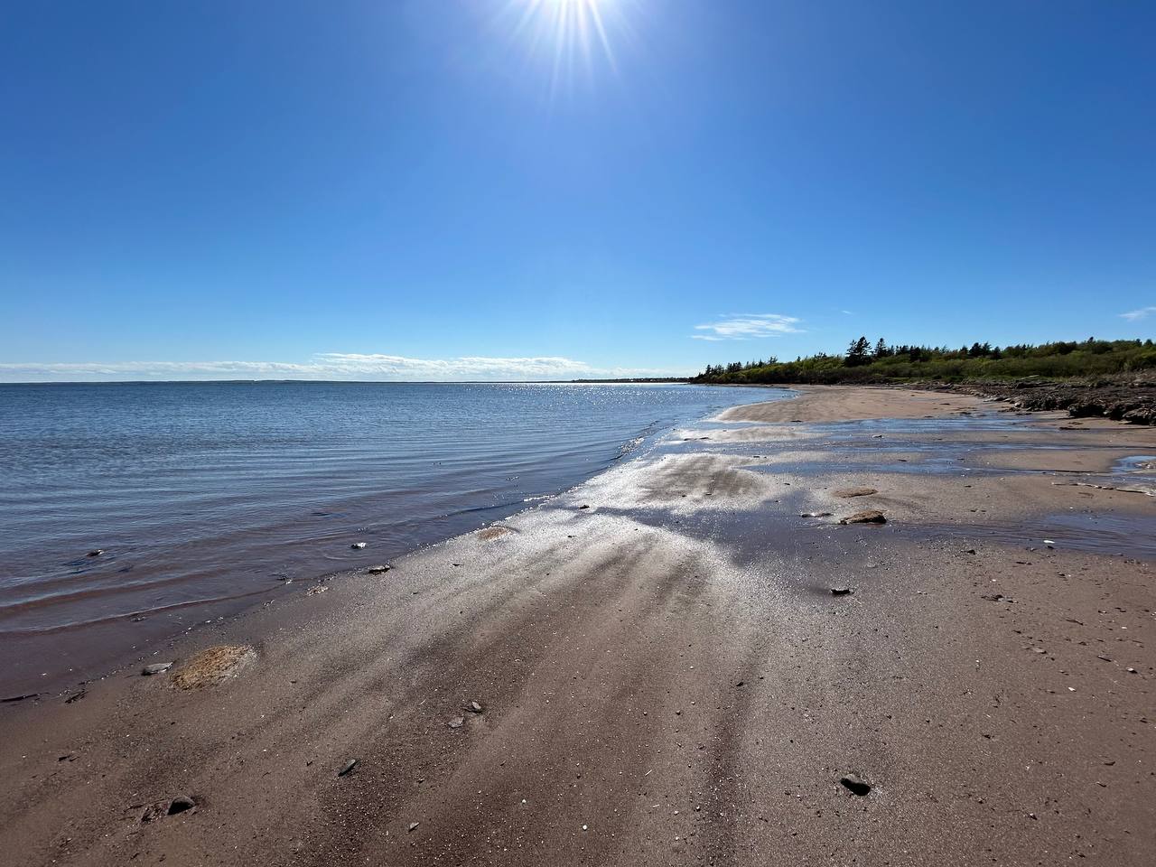 Bright sun over the sandy beach and bay